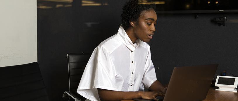 A nonbinary person using a laptop at work.