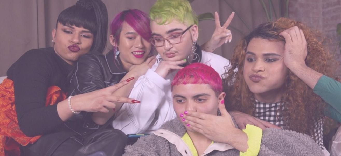 Photo of five friends in their early twenties huddled around one person's camera, posing as though for a selfie. Group is a collection of various races, genders, and hair colors. Photo courtesy of 