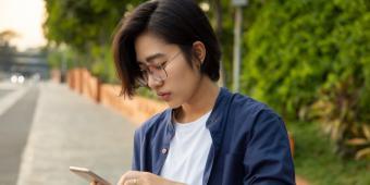 Young Asian nonbinary person peruses social media.